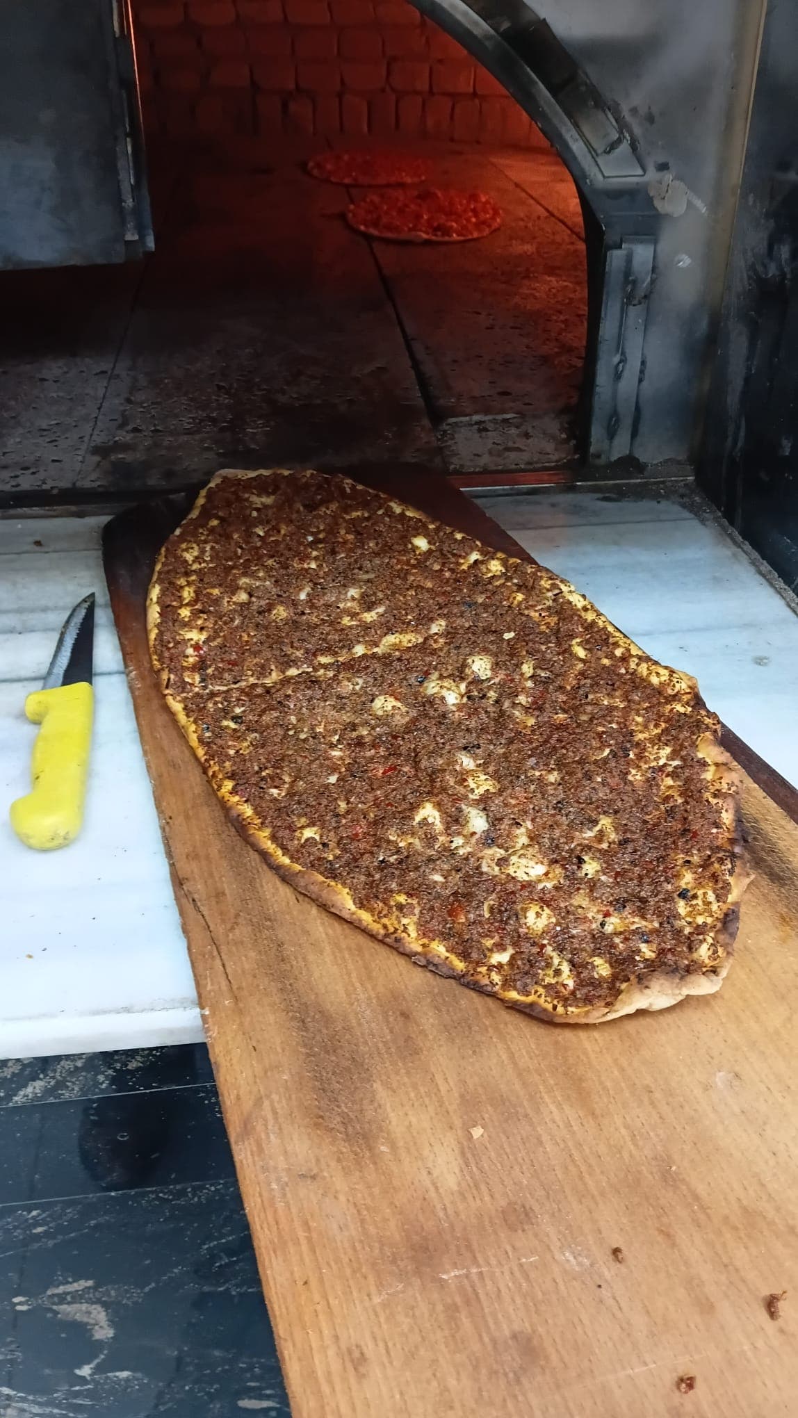 Taş fırın önünde tahta kürek üzerindeki lahmacun
